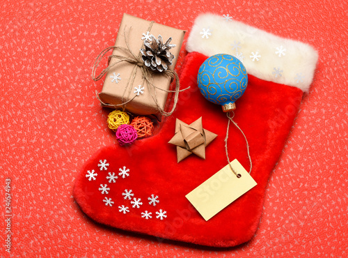 Christmas stocking sock shaped bag. Keep family traditions. Stocking stuffers idea. Santa stocking with christmas gift box. Christmas sock red background top view. Traditional christmas attribute photo