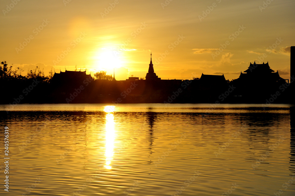 Sunset with a background of Thai temple and a small lake in front of the beautiful view, abstract background