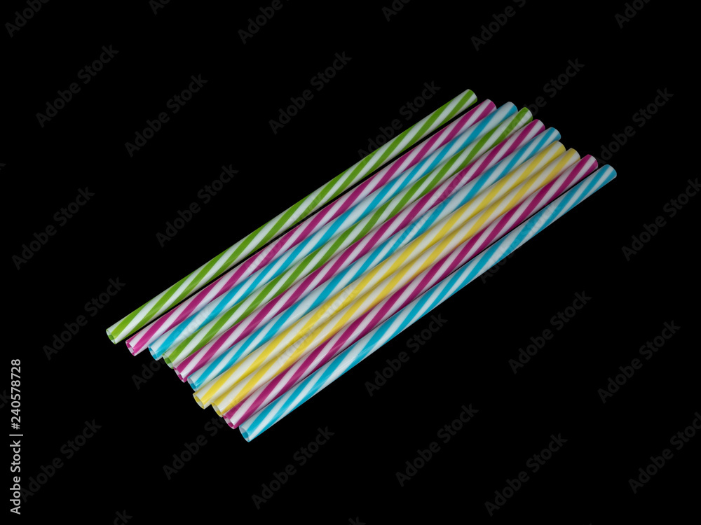 Piles of colorful striped plastic drinking straw, black underground Piles of colorful striped plastic drinking straw, black underground