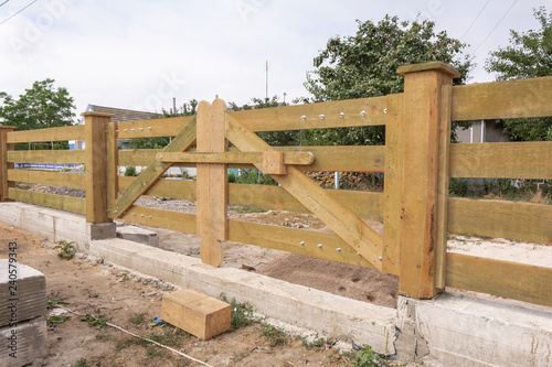 Wooden gates for vehicle entry into the house. Fence in ranch style.