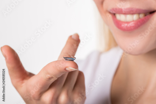 Soft color contact lens on the finger of the female hand on a white background