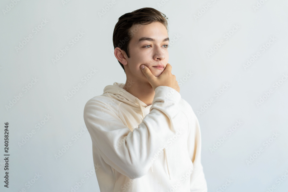 Pensive teen boy touching chin and looking away. Handsome guy thinking. Contemplation concept. Isolated front view on white background. Pensive teen boy touching chin and looking away. Handsome guy thinking. Contemplation concept. Isolated front view on white background.