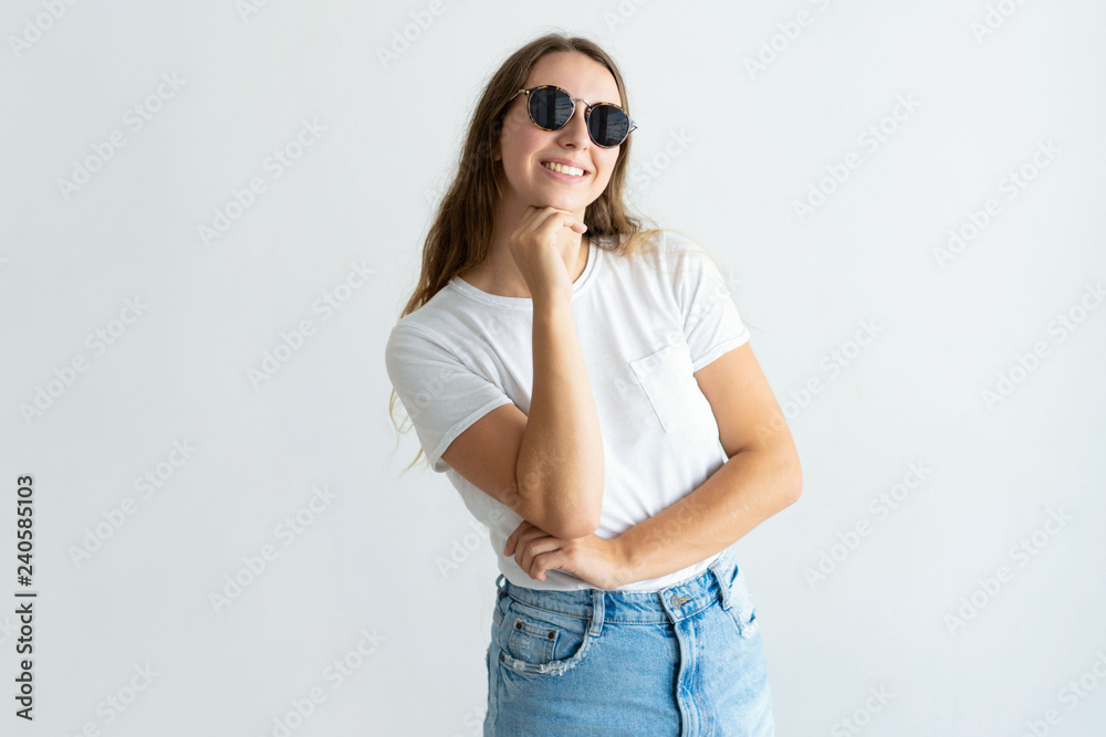 Smiling young woman wearing sunglasses and posing at camera. Girl touching chin and looking at camera. Young woman concept. Isolated front view on white background. Smiling young woman wearing sunglasses and posing at camera. Girl touching chin and looking at camera. Young woman concept. Isolated front view on white background.