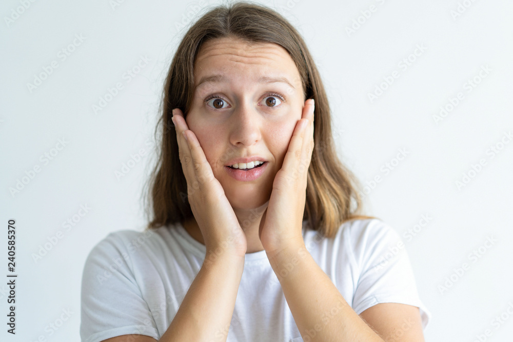 Surprised young woman touching face with both hands. Pretty girl looking at camera. Surprise concept. Isolated front view on white background. Surprised young woman touching face with both hands. Pretty girl looking at camera. Surprise concept. Isolated front view on white background.