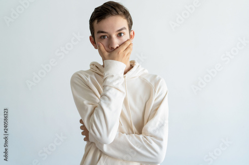 Fotografie Worried teen boy covering mouth with hand