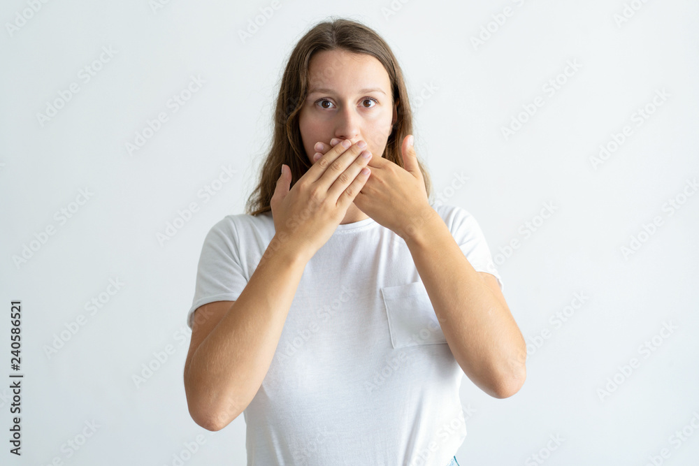 Worried young woman covering mouth with hands. Pretty lady looking at camera. Mistake concept. Isolated front view on white background. Worried young woman covering mouth with hands. Pretty lady looking at camera. Mistake concept. Isolated front view on white background.