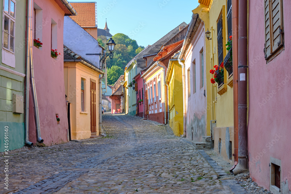  Empty cobbled stone street with colorful houses in the old 18th century historical part of town of Sighisoara