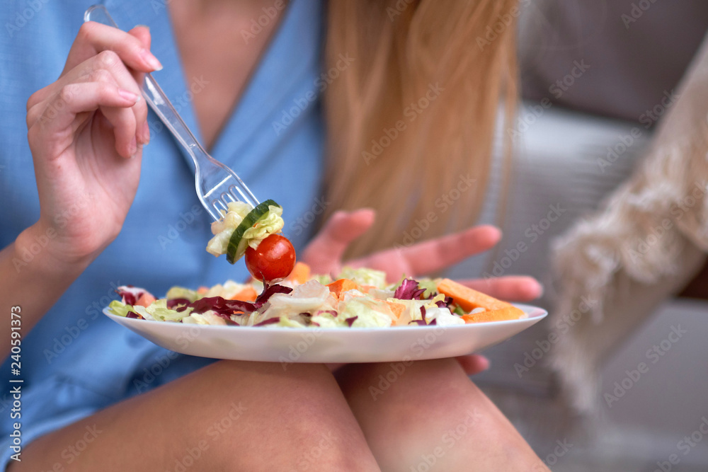 young woman is eating salad at home, diet concept. disgruntled person, depression from having to diet, lack of fat in the diet. young woman is eating salad at home, diet concept. disgruntled person, depression from having to diet, lack of fat in the diet.