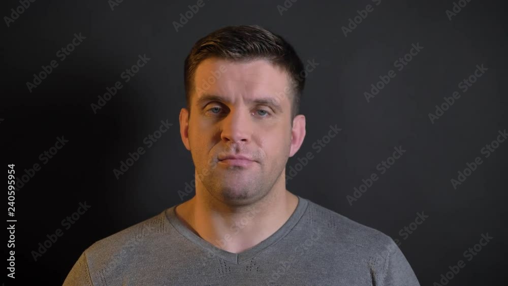 Close-up portrait of middle-aged caucasian man negatively turning her head into camera on black background. Close-up portrait of middle-aged caucasian man negatively turning her head into camera on black background.