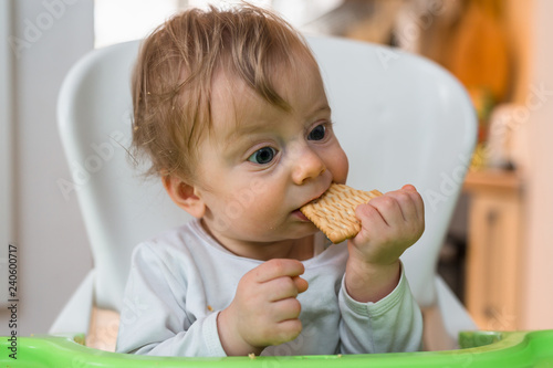 close up of baby boy eating biscuit