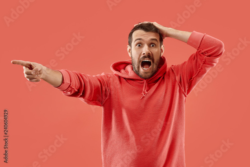 Screaming, hate, rage. Crying emotional angry man screaming on coral studio background. Emotional, young face. male half-length portrait. Human emotions, facial expression concept. Trendy colors