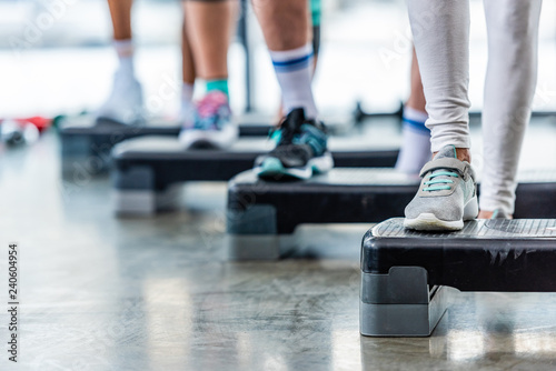 cropped shot of sportspeople doing exercise on step platforms at gym © LIGHTFIELD STUDIOS