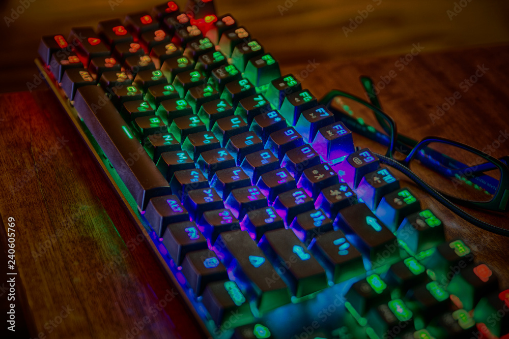Fototapeta premium Podświetlana, zakurzona klawiatura z kolorowymi przyciskami LED RGB, wygląda jak nowoczesne urządzenie do hakowania gadżetów cyberpunk przyszłości z angielskimi i rosyjskimi literami