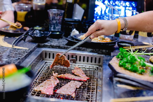 Fototapeta Naklejka Na Ścianę i Meble -  Selective focus to the woman's hand is grilling wagyu beef in Japanese grilled restaurant