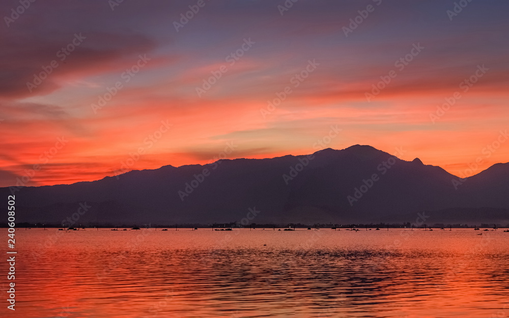 sunset at Kwan Phayao, Lake view evening of colorful red cloudy sky above the hill with reflection on the water, Phayao Province, northern of Thailand.