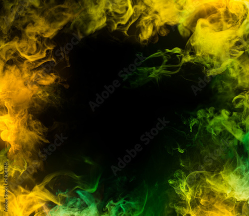 frame from yellow and green smoke over black background
