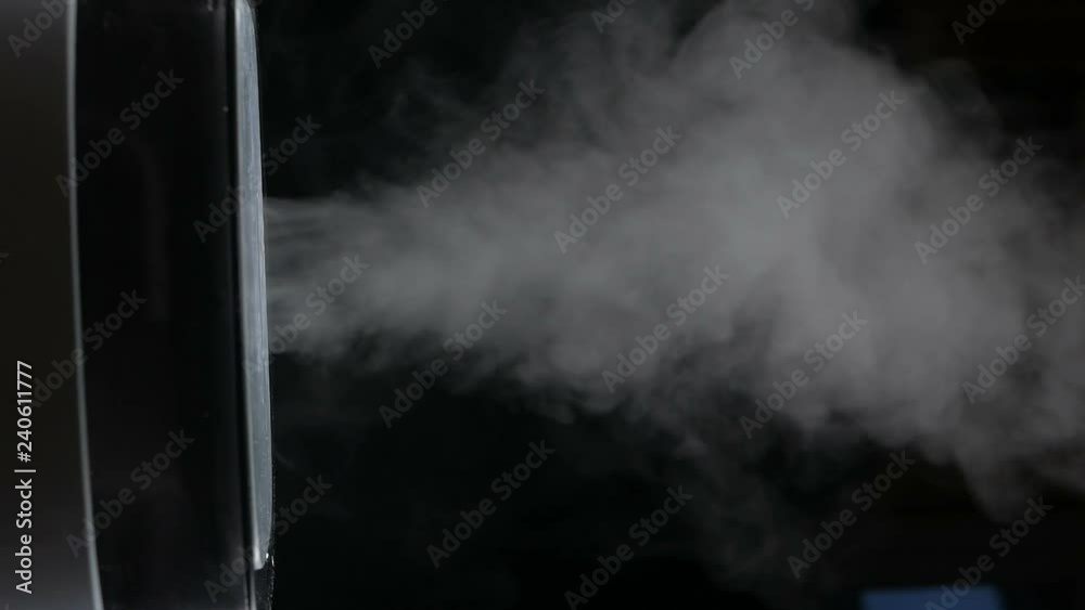 Mist from a black electric humidifier & oil diffuser in a dark room