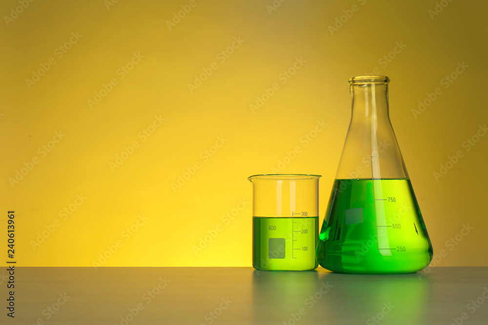 Chemistry laboratory glassware with samples on table against color background Chemistry laboratory glassware with samples on table against color background