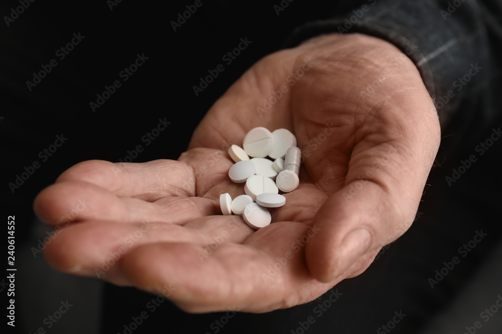Senior man holding pills in his hand, closeup Senior man holding pills in his hand, closeup