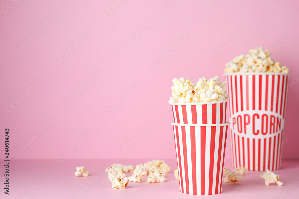 Tasty popcorn in paper cups on color background. Space for text
