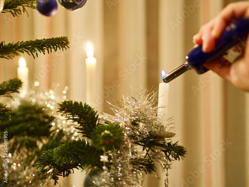 Eine Person zündet zu Weihnachten Kerzen auf dem Christbaum an