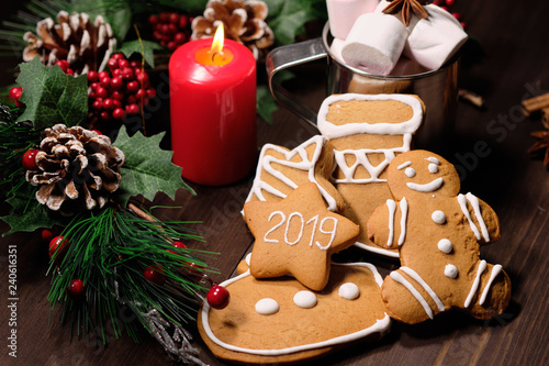 ginger biscuit and coffee with milk in the iron cup on brown wood background with Christmas tree 