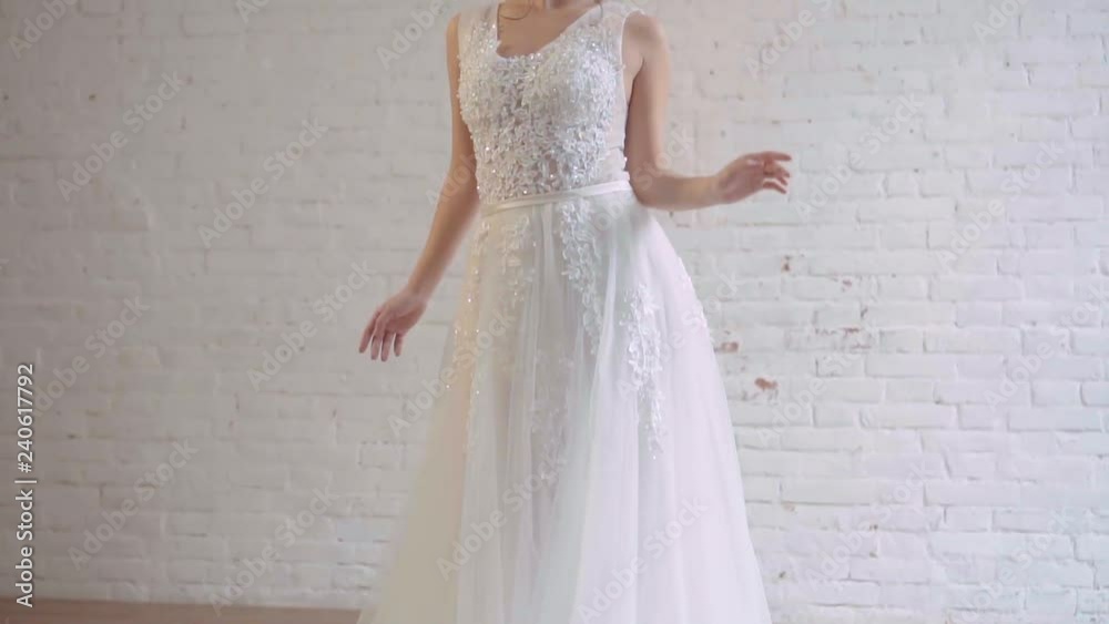 attractive girl in a light white luxury white wedding dress poses, stands alone in a spacious room, prepares for the holiday, slowly lowers her hand and lifts her head and looks into the distance attractive girl in a light white luxury white wedding dress poses, stands alone in a spacious room, prepares for the holiday, slowly lowers her hand and lifts her head and looks into the distance