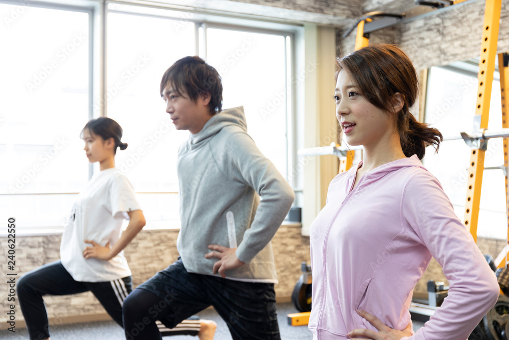 Obraz premium ジムでストレッチをする男女3人