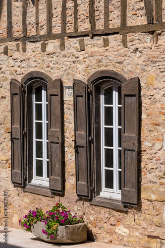 a brick wall with windows and wooden shutters