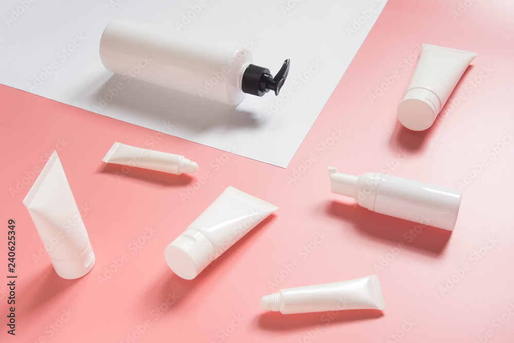 Fototapeta premium Cosmetic products collection. Blank white cosmetic bottle/tube on pink and white background. Branding mock-up for lotion, cream, gel, foam, soap or shampoo. Minimal style. Beauty blogger concept.