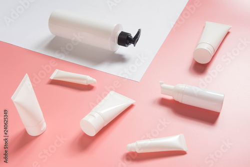 Cosmetic products collection. Blank white cosmetic bottle/tube on pink and white background. Branding mock-up for lotion, cream, gel, foam, soap or shampoo. Minimal style. Beauty blogger concept.