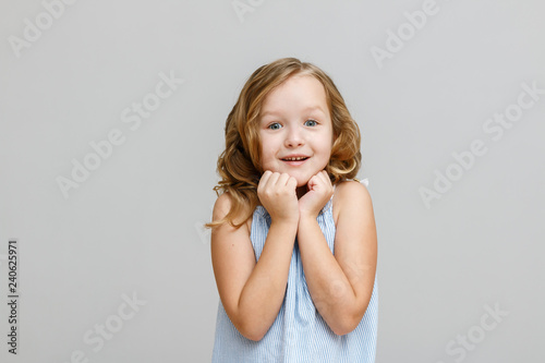 Portrait of a little girl on a gray background. The child is loo