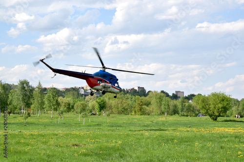 гражданский вертолет взлетает с поля в городе