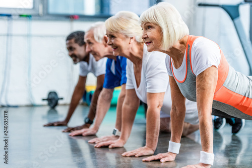 side view of mutiethnic senior athletes doing plank at sports hall