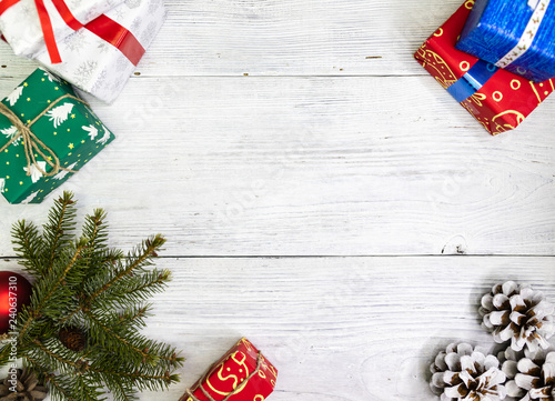 Gifts in festive color packaging and Christmas tree branches, lie on a white wooden background. Christmas decorations. New Year, Christmas, Saint Nicholas, Santa.