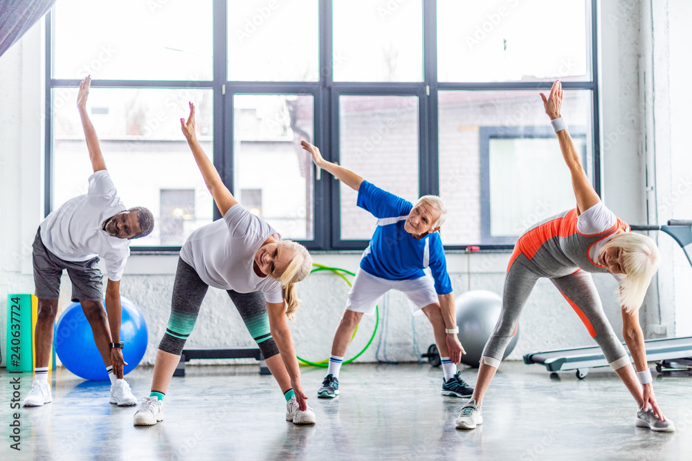 multiethnic senior sportspeople synchronous exercising at sports hall