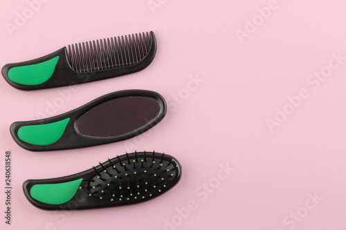 A set of different hair brushes and a mirror in one style on a bright pink background. view from above