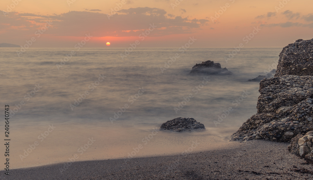 Obraz premium Nerja, Malaga, Andalusi, Spain - November 17, 2018: Nice sunrise on Burriana beach, village of Nerja, Spain