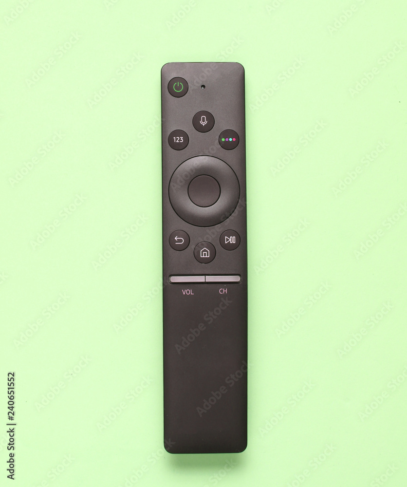 Modern TV remote control on a green pastel background. Top view, minimalism.