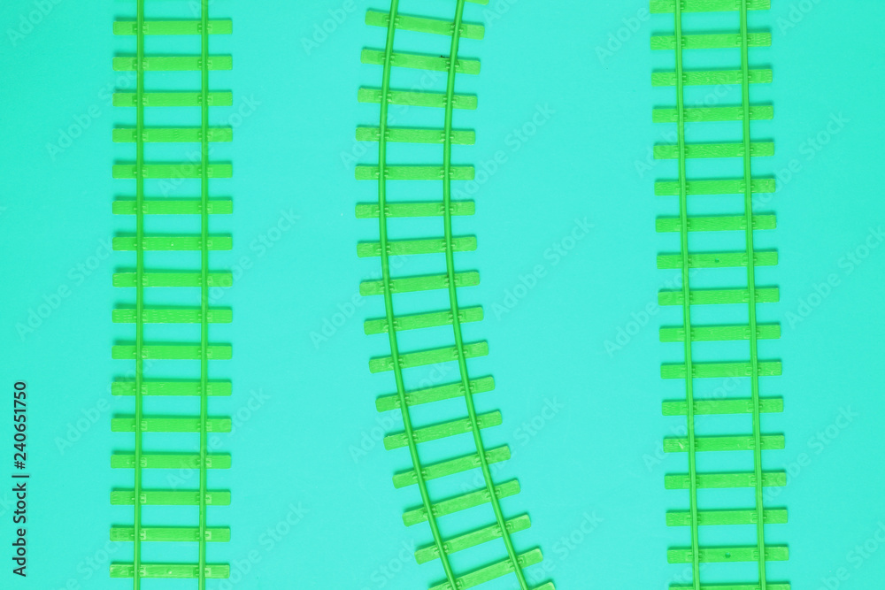 Toy railroad tracks on blue acid background. Top View.