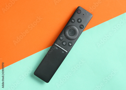 A modern TV remote control on orange blue background. Top view, minimalism.