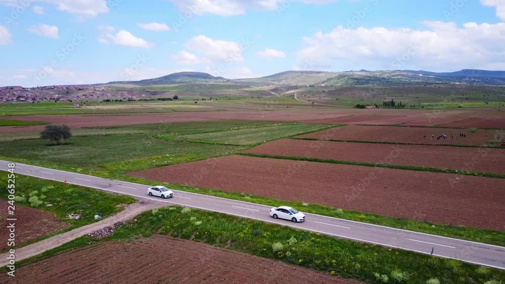 Aerial view electric car driving on country road, luxury car driving through mist at dusk with headlights Aerial view electric car driving on country road, luxury car driving through mist at dusk with headlights
