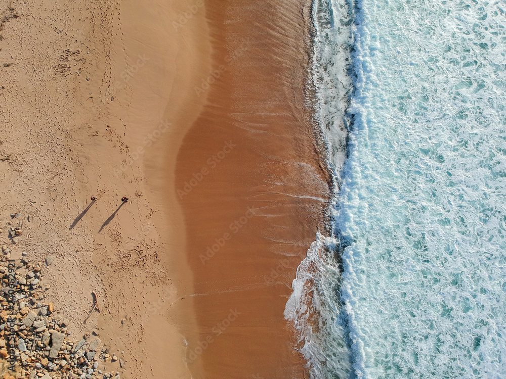 Aerial view from a couple walking in a sandy beach. Drone photo