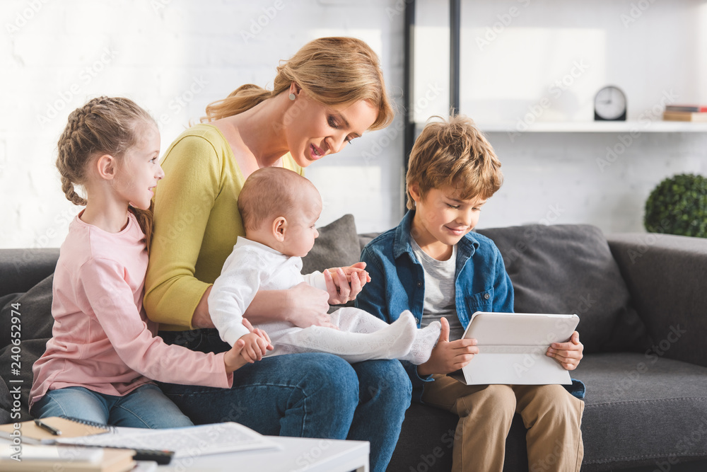 beautiful happy mother with three adorable children sitting together on sofa beautiful happy mother with three adorable children sitting together on sofa