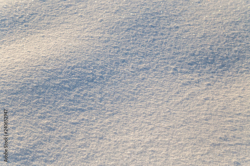 Background of white snow sparkling in the sun. Shallow depth of field