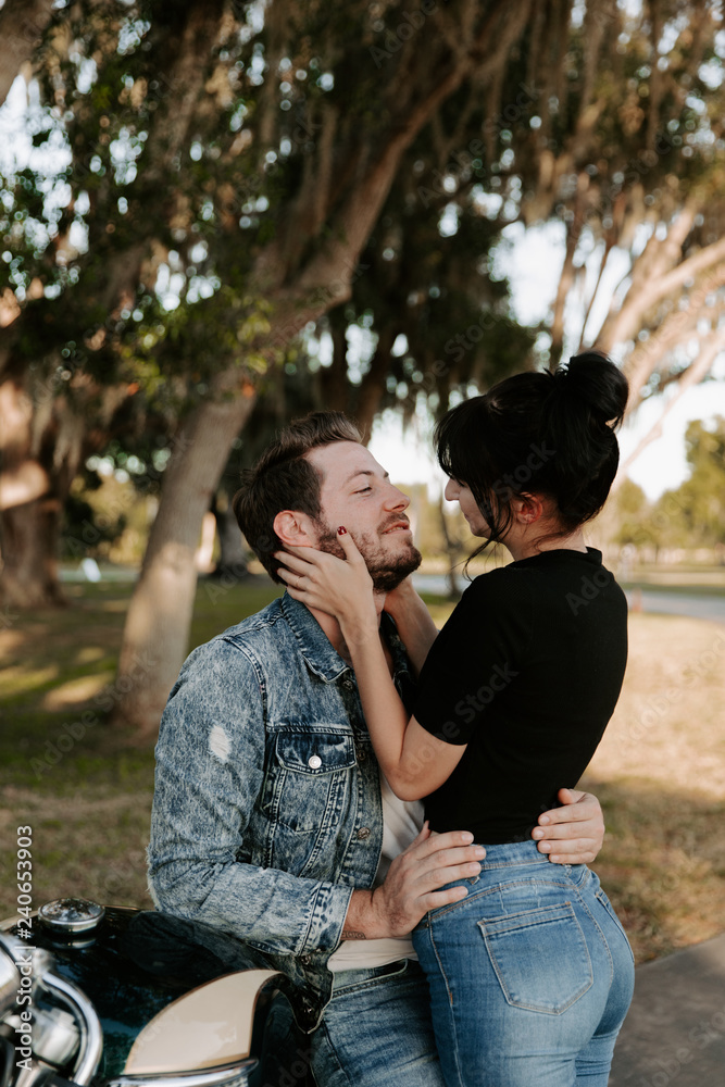 Loving Adorable Portrait of two Attractive Good Looking Young Adult Modern Fashionable People Guy Girl Couple on Classic Green Motorcycle Hugging, Kissing, Holding, and Looking into each Other’s Eyes Loving Adorable Portrait of two Attractive Good Looking Young Adult Modern Fashionable People Guy Girl Couple on Classic Green Motorcycle Hugging, Kissing, Holding, and Looking into each Other’s Eyes