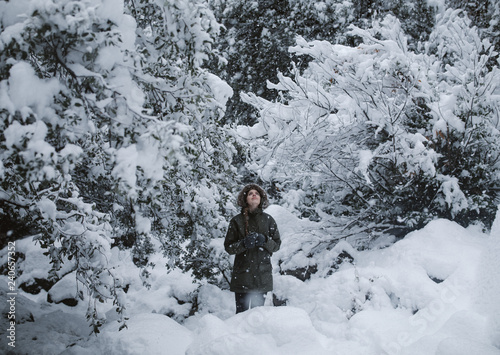 woman hiking in the woods during a snow storm in winter