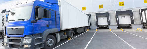 Loading dock of large warehouse with blue cabin truck under loading