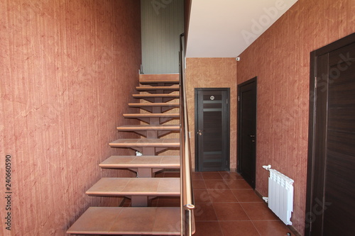 Open staircase with stone steps going up to the inside corridor rooms close-up on a background of bright walls and dark doors