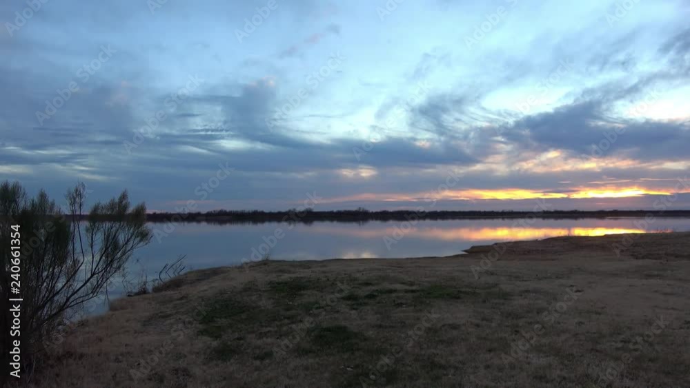 View of beautiful landscape with the lake and colorful reflections of clouds on the water at sunset. View of beautiful landscape with the lake and colorful reflections of clouds on the water at sunset.